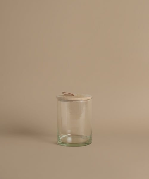 A glass canister against a beige background.