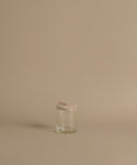 A glass canister against a beige background.