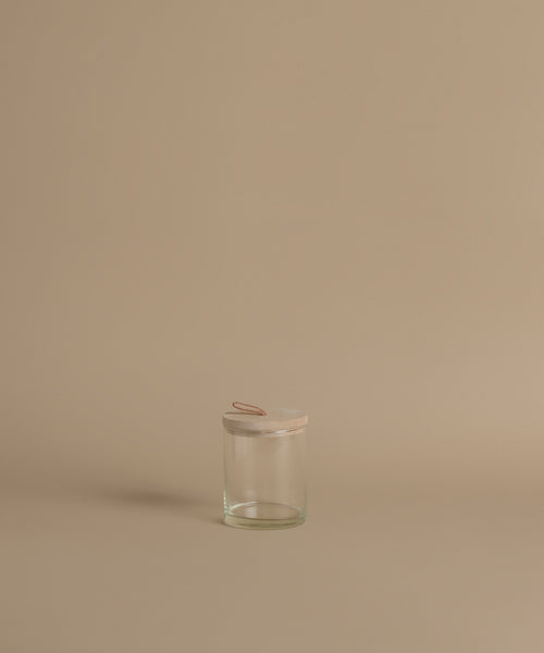 A glass canister against a beige background.