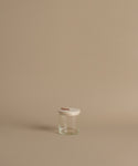 A glass canister against a beige background.