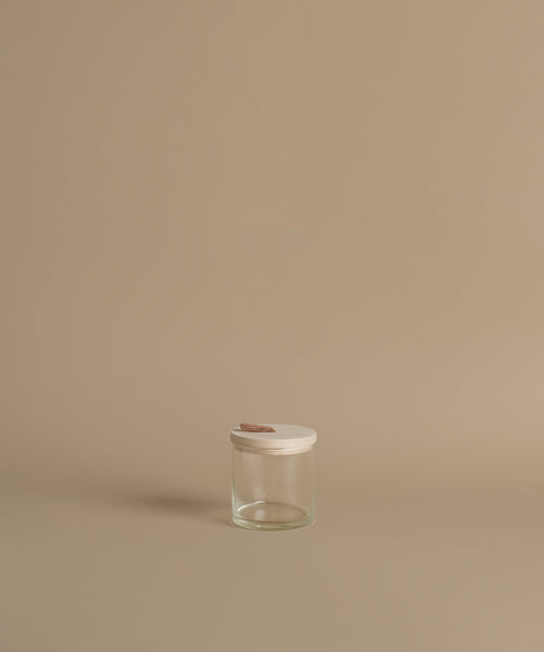 A glass canister against a beige background.