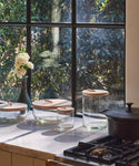 Glass canisters in front of a window in a kitchen.