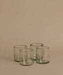 Recycled glass cups against a beige background.