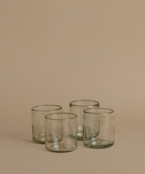 Recycled glass cups against a beige background.