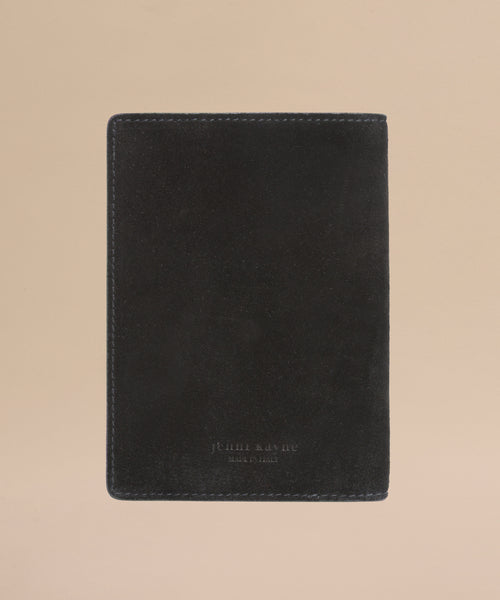 The Suede Passport Holder in black features subtle edge stitching and is displayed on a light beige background—an elegant touch for your travel essentials.