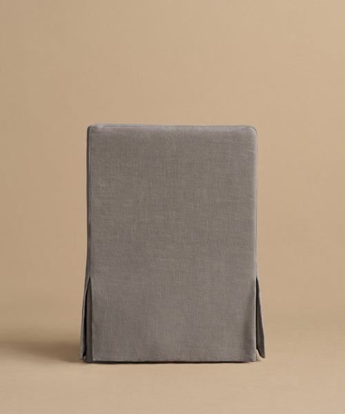 The Sunset Dining Arm Chair features a straight back and a fitted gray slipcover with subtle seams and two side slits, shown from the back against a plain beige background.