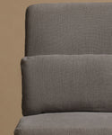 Close-up of a textured gray upholstered chair or sofa cushion against a warm beige background.