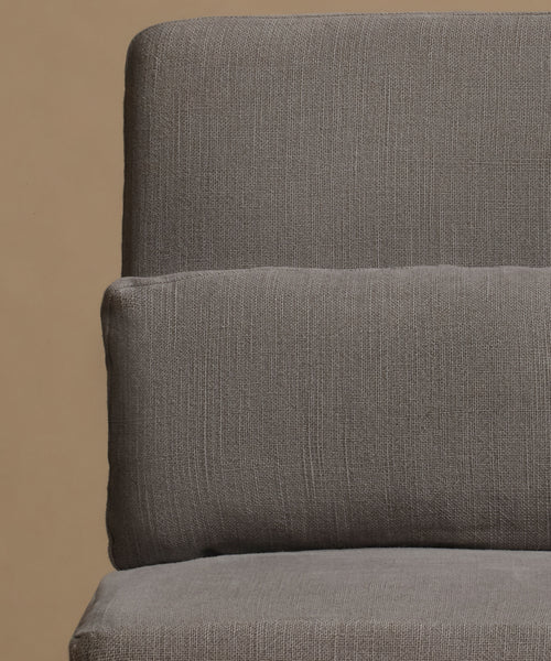 Close-up of a textured gray upholstered chair or sofa cushion against a warm beige background.