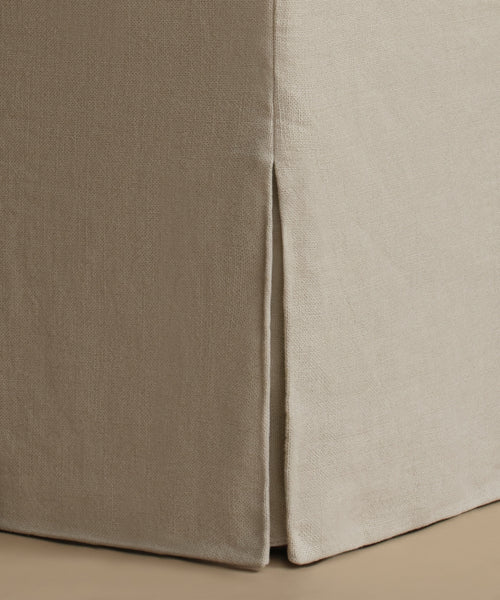 Close-up of a beige upholstered furniture corner with a visible seam and textured fabric surface.