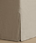 Close-up of a beige upholstered furniture corner with a skirted edge and visible fabric texture.