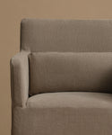 Close-up of a textured taupe fabric armchair with a matching back cushion against a solid beige background.