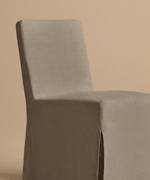 The Sunset Dining Chair features a high, straight back and a full taupe linen slipcover, displayed against a plain beige background.
