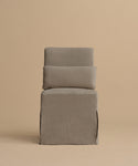 The Sunset Dining Chair features a boxy silhouette, tall rectangular back and seat upholstered in taupe linen with a loose-fitting slipcover, shown against a plain beige background.