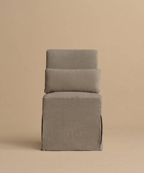 The Sunset Dining Chair features a boxy silhouette, tall rectangular back and seat upholstered in taupe linen with a loose-fitting slipcover, shown against a plain beige background.