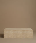 A rectangle travertine coffee table against a beige background.