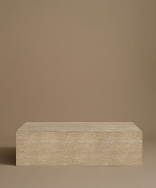 A rectangle travertine coffee table against a beige background.