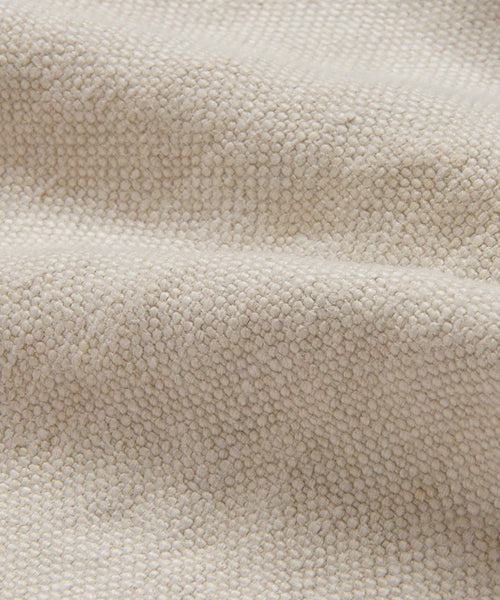 A close-up of the Fabric Swatch Drift Linen highlights its beige, boucle-style surface with soft texture, small looped yarns, and a subtly wavy appearance.