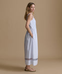 Woman wearing a light blue dress against a beige backdrop. 