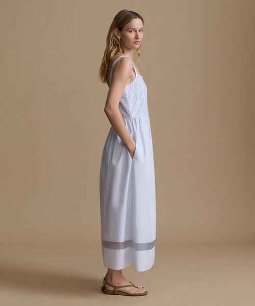 Woman wearing a light blue dress against a beige backdrop. 