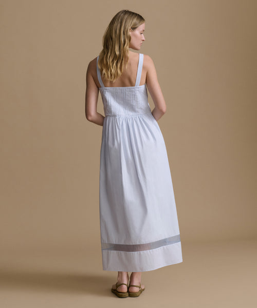 Woman wearing a light blue dress against a beige backdrop. 
