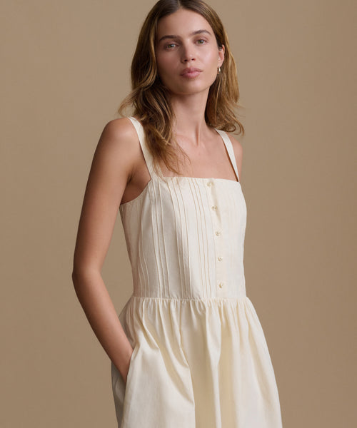 Woman wearing an ivory dress against a beige backdrop.