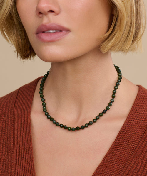 A woman with short blonde hair models the Tiny Boule Collar, paired with a rust V-neck top, her lower face, neck, and upper chest shown against a neutral background.