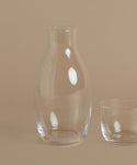 A glass carafe against a beige background.