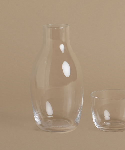 A glass carafe against a beige background.