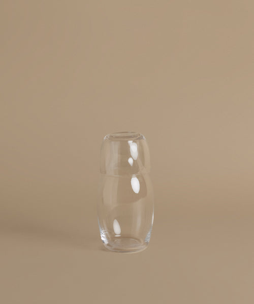 A glass carafe against a beige background.