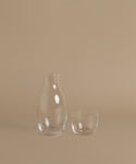 A glass carafe against a beige background.