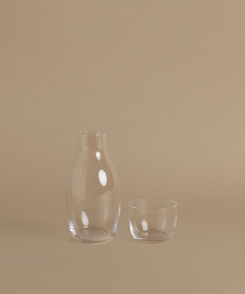 A glass carafe against a beige background.