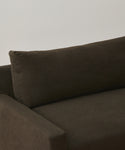 A close-up of the Harbor Sofa, featuring modern design in dark brown linen upholstery with visible armrest, seat cushion, and backrest set against a plain, light-colored wall.