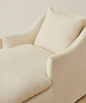 A close-up of the Miramar Chaise, a modern cream-colored upholstered armchair with plush cushion and matching pillow, styled for luxury and set against a neutral background.