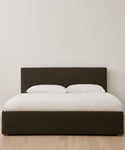 The Pacific Bed Warehouse Sale offers a modern bed with a dark upholstered headboard and frame, white bedding and pillows, all set on a light wooden floor—an ideal choice for updating any contemporary bedroom.