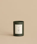 A minimalist Vail Glass Candle, hand-poured with a holiday scent, features a white label reading Jenni Kayne Vail Clove Bud & Siberian Juniper, 10oz / 283g, set against a beige background.