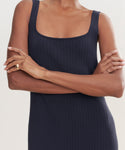 A person stands with arms crossed, wearing the Rib Tank Dress in dark navy. Cropped at shoulders and mid-thigh, the image highlights their two rings and showcases this versatile sleeveless style for warm weather.