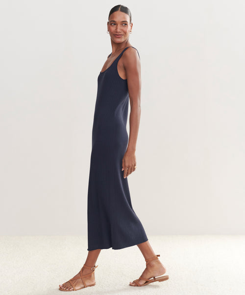 A woman smiles sideways in an ankle-length, sleeveless Rib Tank Dress in dark navy with tan strappy flats—a perfect warm-weather staple—set against a plain light background.