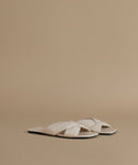 Pair of white sandals on a beige background