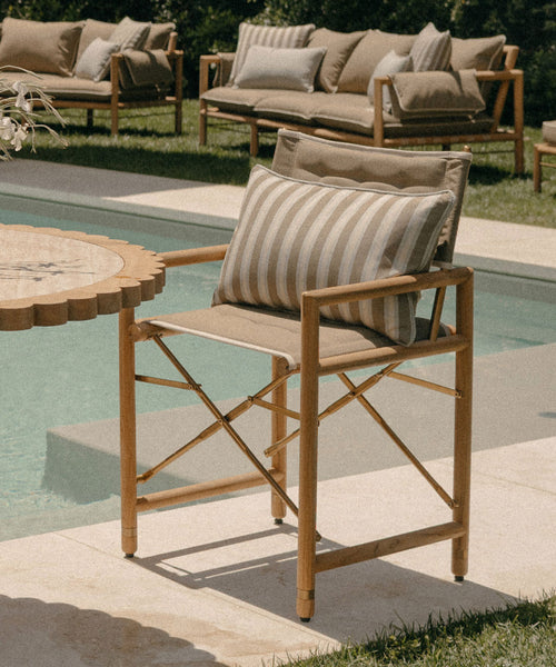 Wooden outdoor chair with striped cushion near a poolside setting