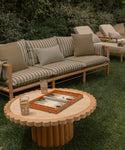 Outdoor seating area with a sofa, table, and lounge chairs in a garden setting.