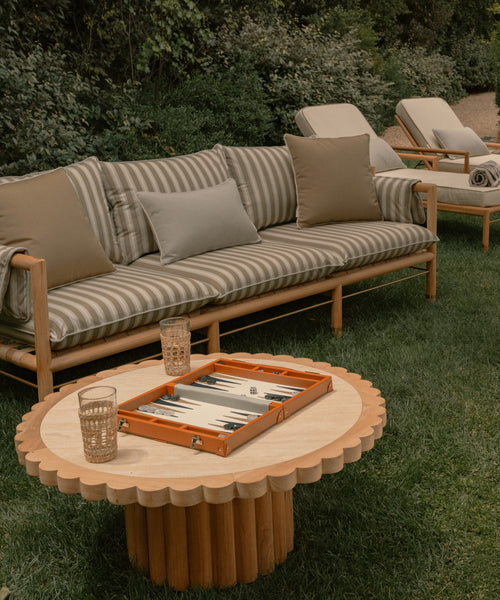 Outdoor seating area with a sofa, table, and lounge chairs in a garden setting.