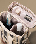 Open beige travel bag with bottles inside on a beige background