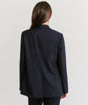 Seen from behind, a person with long brown hair wears the Brentwood Blazer—an effortless display of classic tailoring set against a simple light background.