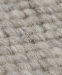Close-up of the Rug Swatch displays thick, chunky light gray and beige fibers in a woven texture. Visible loops and strands give this swatch a soft, natural lodge-style appearance.