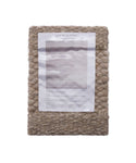 A Rug Swatch of chunky, handwoven beige wool with a Jenni Kayne product info sheet attached to the front, displayed against a plain white background.
