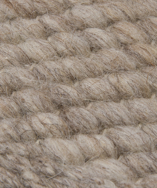 Close-up of a woven, chunky beige and light brown wool fabric with visible fibers and textured braids, similar to a Rug Swatch in warm walnut tones.
