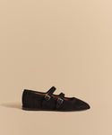 The Wren Flat is a black Mary Jane shoe featuring double straps and a sleek, pointed toe.