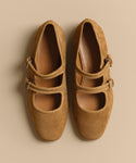 A pair of Wren Flat tan suede Mary Jane shoes with rounded square toes and double buckle straps, displayed side by side on a beige background.