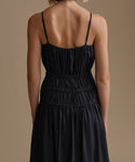 Black wynn dress with thin straps on a person against a beige background