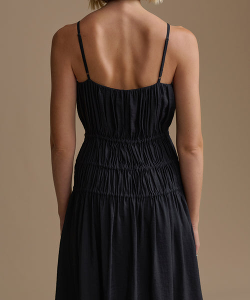 Black wynn dress with thin straps on a person against a beige background